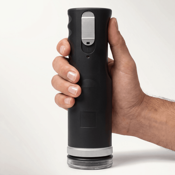 Hand holding the black Lovebotz Master Bot Super Powered Automatic Stroker upright, silver slider switch visible