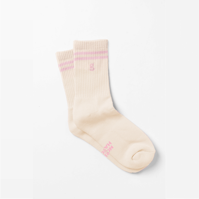 A pair of nude color crew socks with 2 pink lines at the top and pink logo of Girls Get Off "g" underneath the lines including phrases of "spread legs" and "not hate"