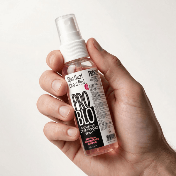 A hand holding a clear spray bottle of ProBlo Strawberry Numbing Deep Throat Spray against a plain background.