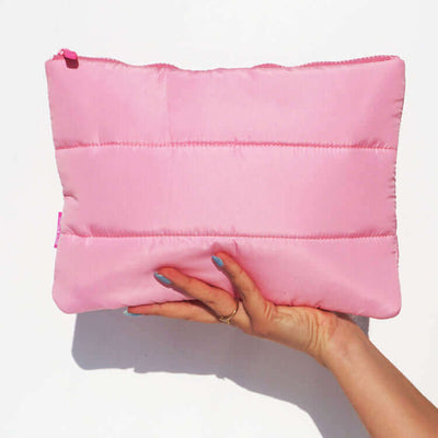 Pink bag used for storing sex toys, puffy pink, front view held by a hand