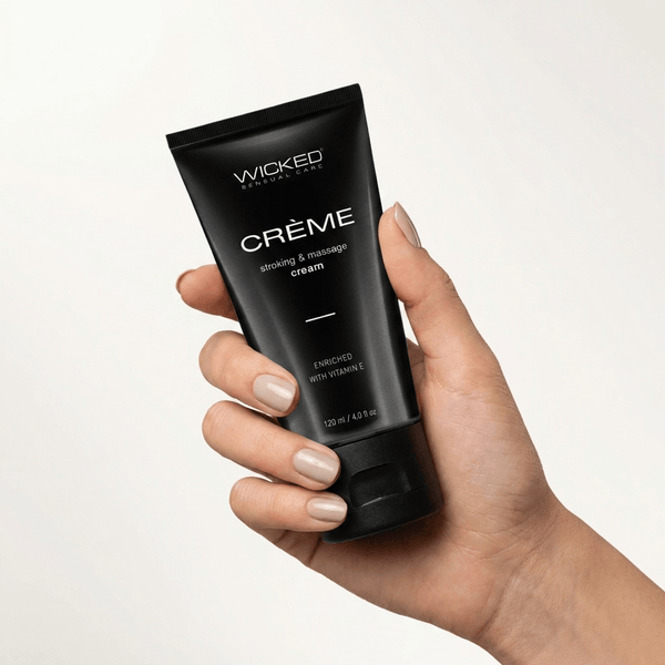 Hand holding a black tube of Wicked Stroking and Massage Cream enriched with vitamin E, 4 oz