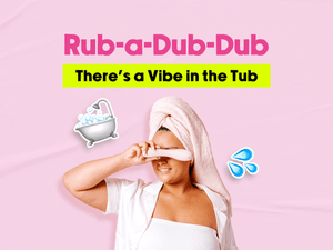 - Graphic featuring a woman with towel wrapped around her head holding a light pink vibrator on her eyes. The playful pink design includes bubble bath and water droplet emojis and a text says 'Rub-a-Dub-Dub'