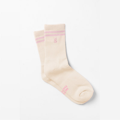 A pair of nude color crew socks with 2 pink lines at the top and pink logo of Girls Get Off "g" underneath the lines including phrases of "spread legs" and "not hate"