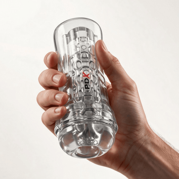 A hand holding a clear, textured PDX Elite ViewTube EZ-Grip Stroker against a plain background.
