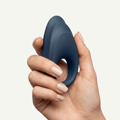 A hand holding Satisfyer Strong One on an off-white background