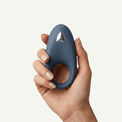A hand holding  Satisfyer Strong One on an off-white background