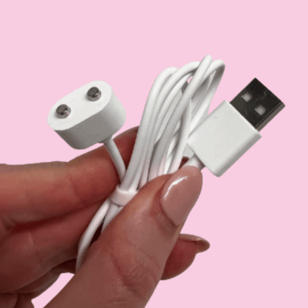 Hand holding a white USB cable against a pink background