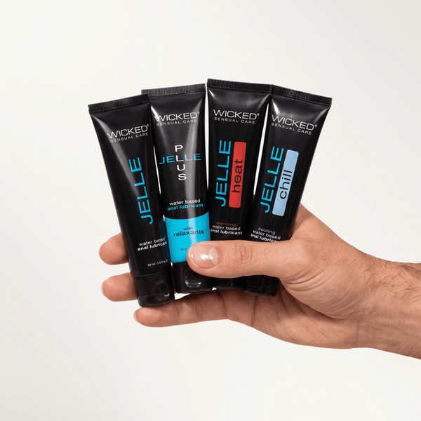 Hand fanning out the four tubes of the Wicked Anal Adventure Lube Kit: Jelle, Plus, Heat and Chill
