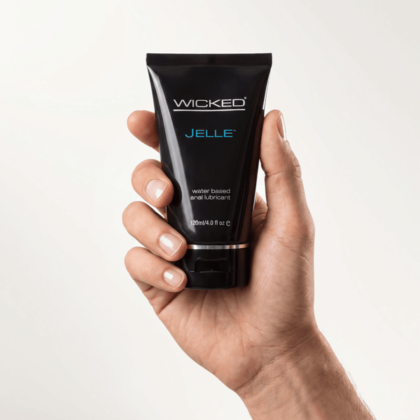 Wicked Anal Jelle Water-Based Anal Lube 4 oz black tube held in a hand