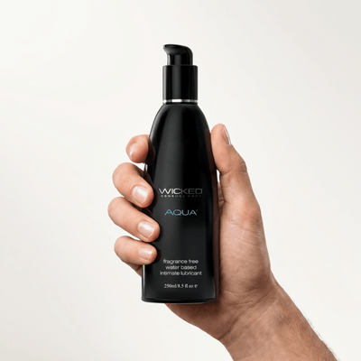 Hand holding the 8.5 oz Wicked Aqua Water Based Lube fragrance free black pump bottle