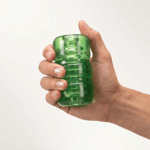 A hand holding a translucent green, ribbed pocket stroker against a plain background.